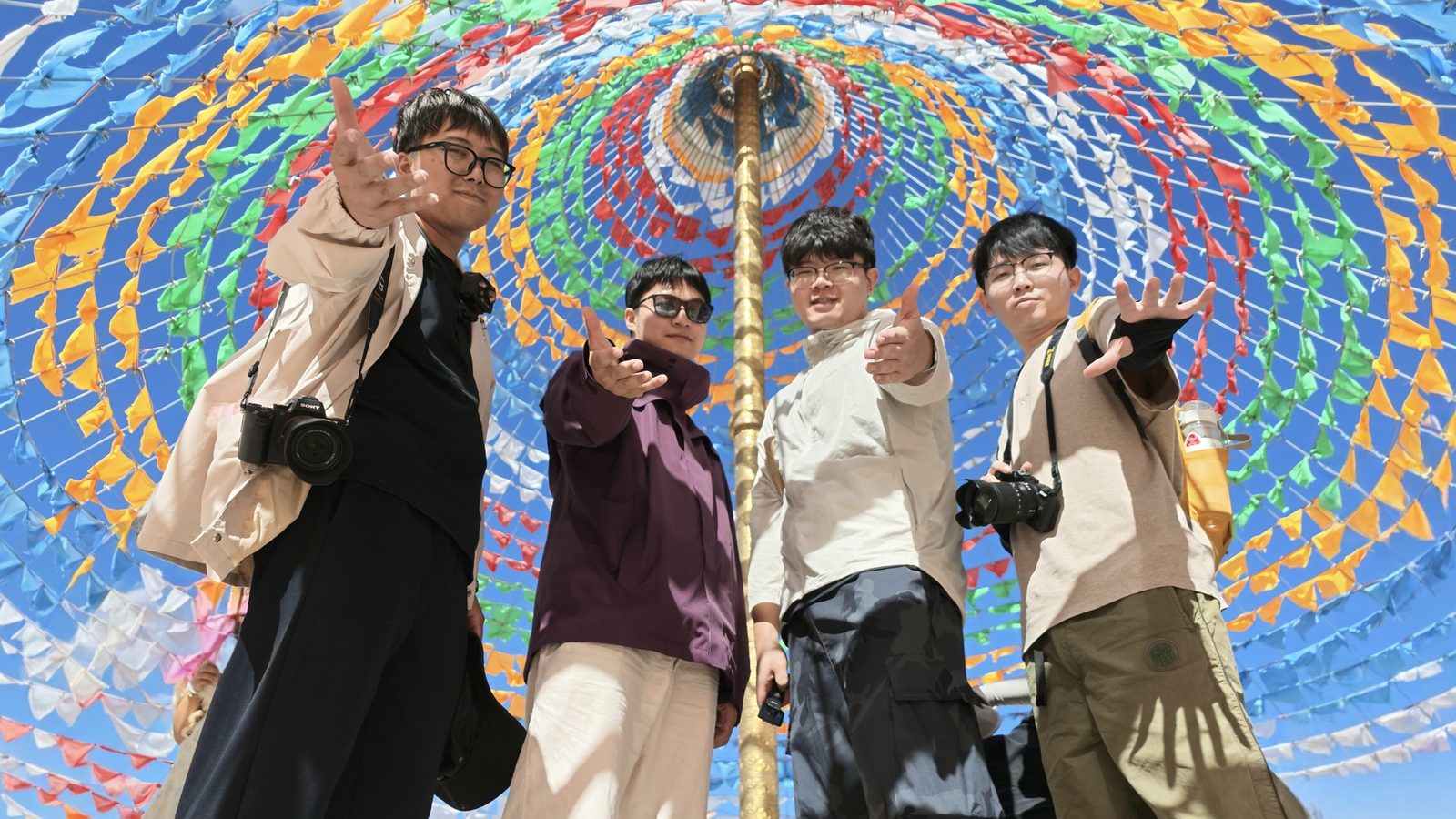 4 个男生在五彩经幡下合影，由分离屏远距离操控